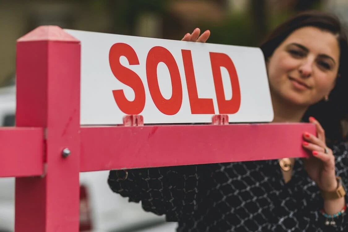 real estate agent putting up “sold” sign