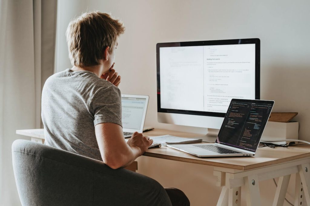 man sitting in front of three computer screens