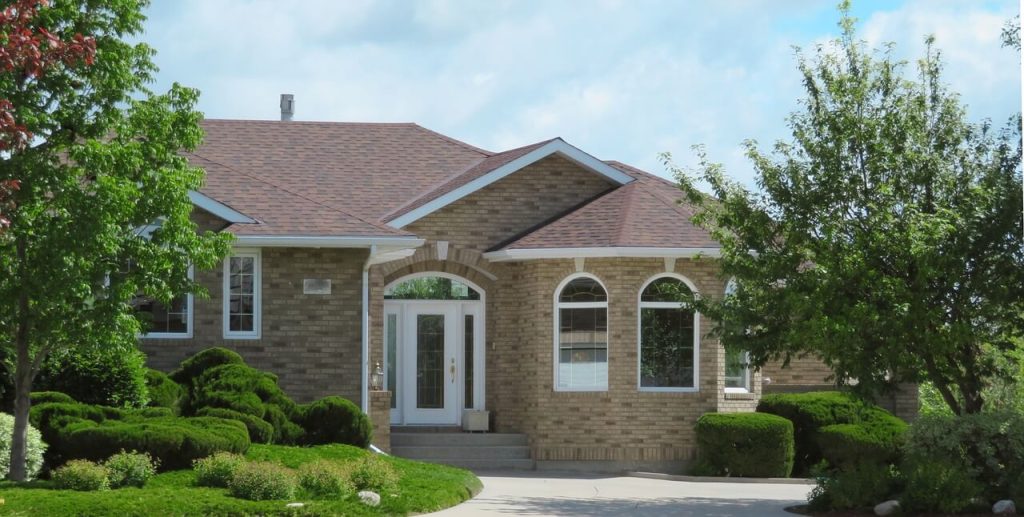 brown suburban home with manicured hedges